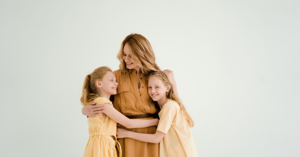 Mãe abraçando as duas filhas