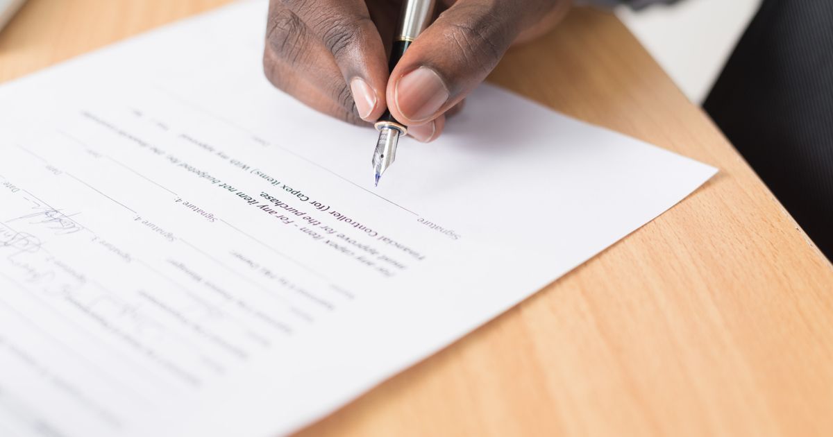 Mão assinando contrato com caneta