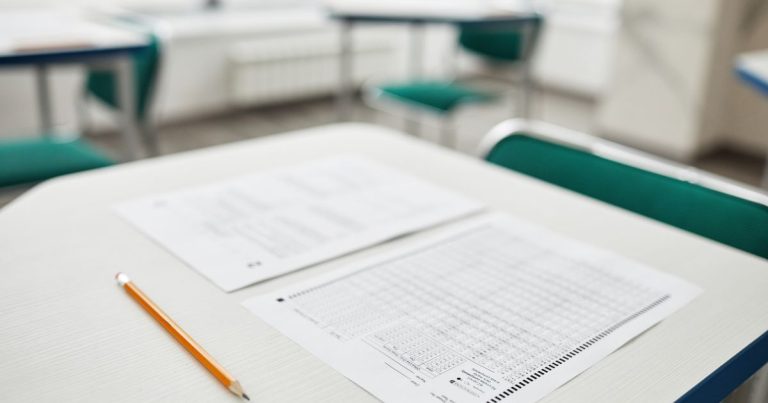 Close-up de provas e um lápis em uma mesa de sala de aula, prontos para um teste.