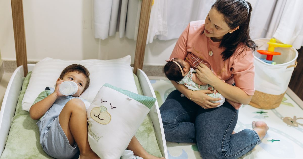 Mãe com bebê e criança pequena em casa