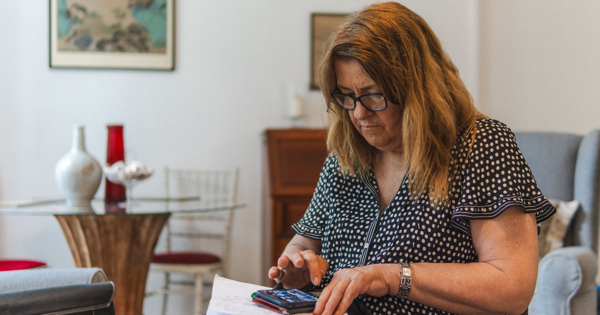 Mulher calculando com calculadora e documentos
