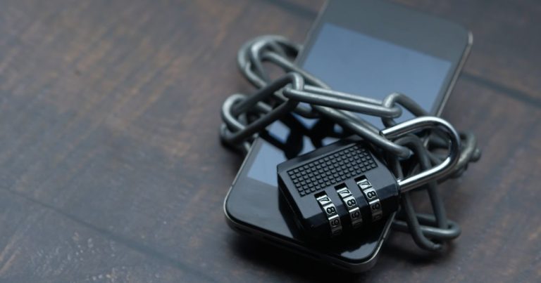 Smartphone envolto em corrente com cadeado, simbolizando proteção de dados
